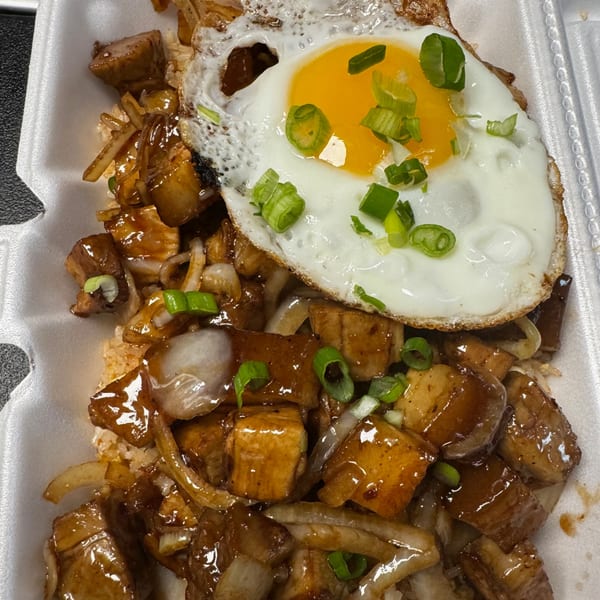 So-Ju Chikn's Korean dish with glazed chicken, onions, rice, and a fried egg with green onions.
