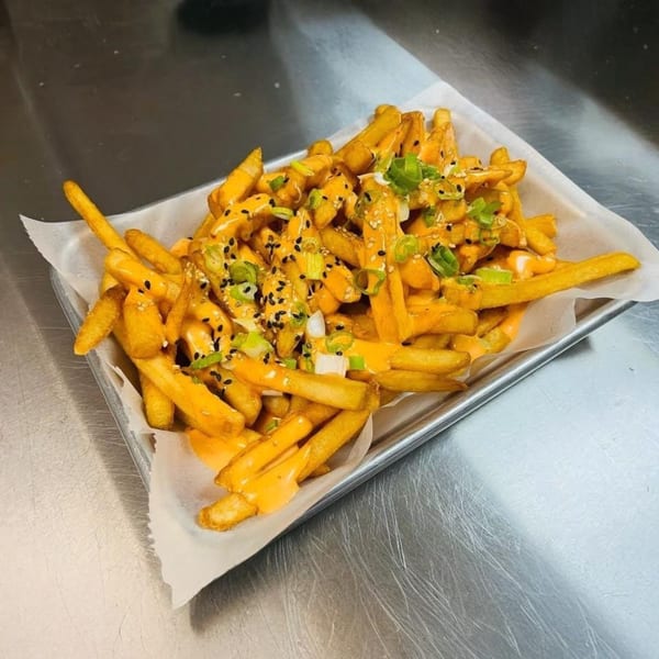 So-Ju Chikn's Korean fries, topped with cheese sauce, sesame seeds, and green onions.